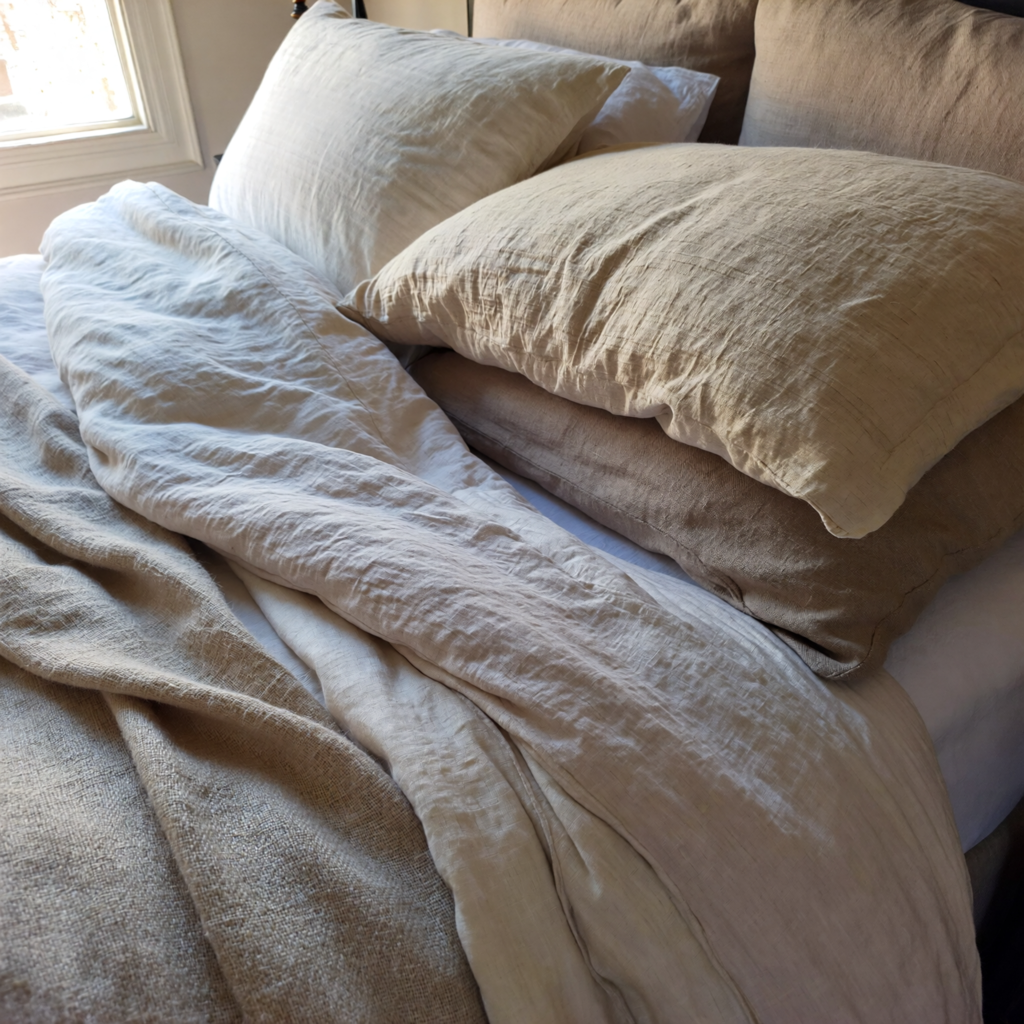 Layered linen bedding in warm neutral tones creating a cozy romantic bedroom feel