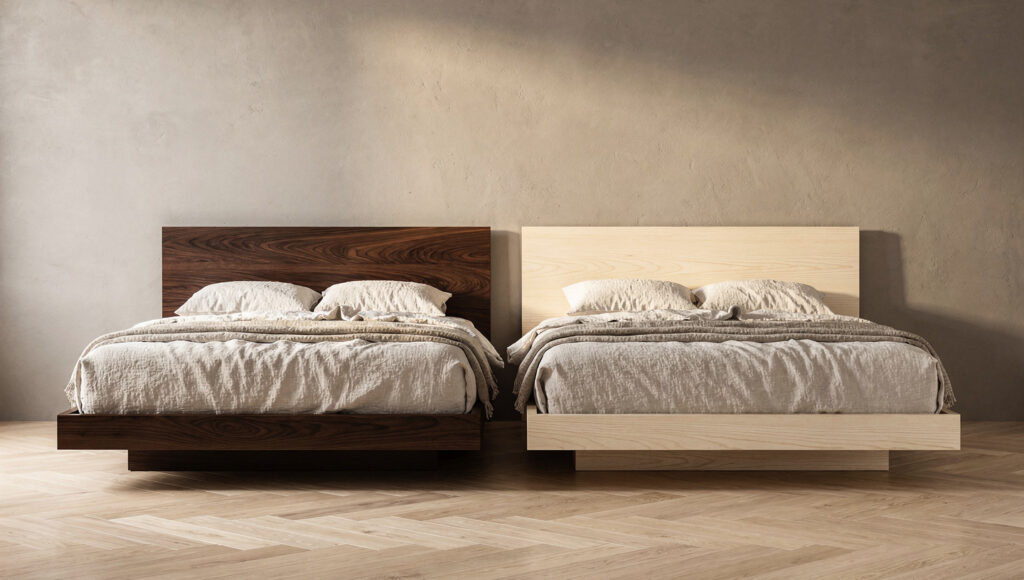 A side-by-side comparison of two low-profile Japandi platform beds against the same warm greige limewash wall — dark walnut on the left showing rich chocolate-brown grain reading as visually heavy and grounding, white oak on the right showing pale warm honey grain nearly disappearing into the wall and reading as expansive