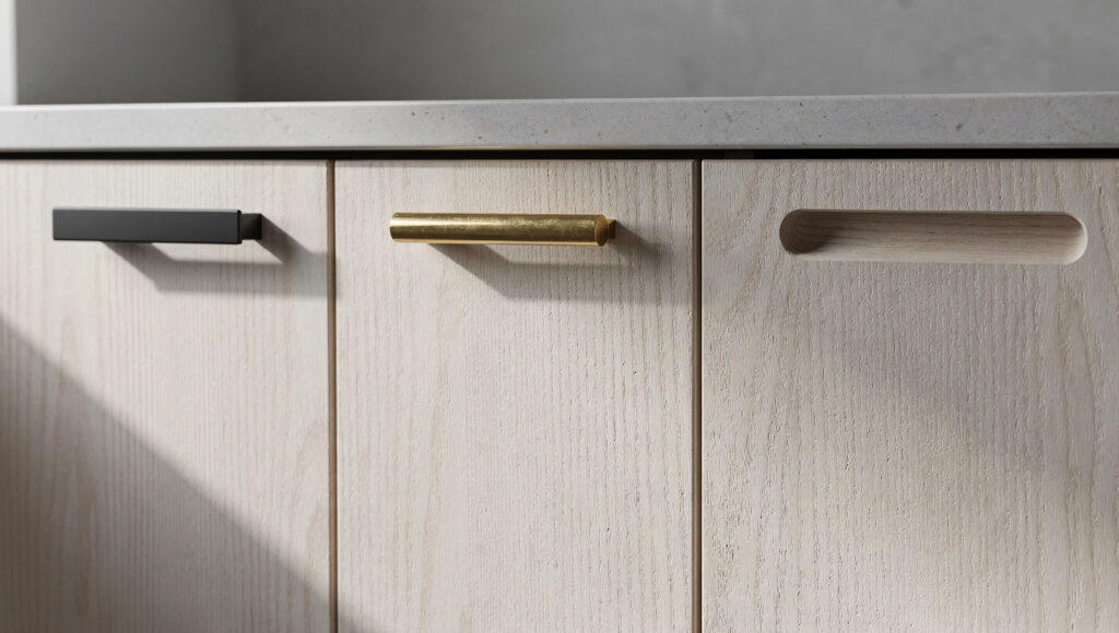 Three Japandi kitchen hardware approaches on adjacent rift-sawn white oak flat-panel cabinet doors — a slim matte black square bar pull on the left, an unlacquered brass bar pull showing natural patina variation in the center, and an integrated finger-pull routed into the door edge with no applied hardware on the right