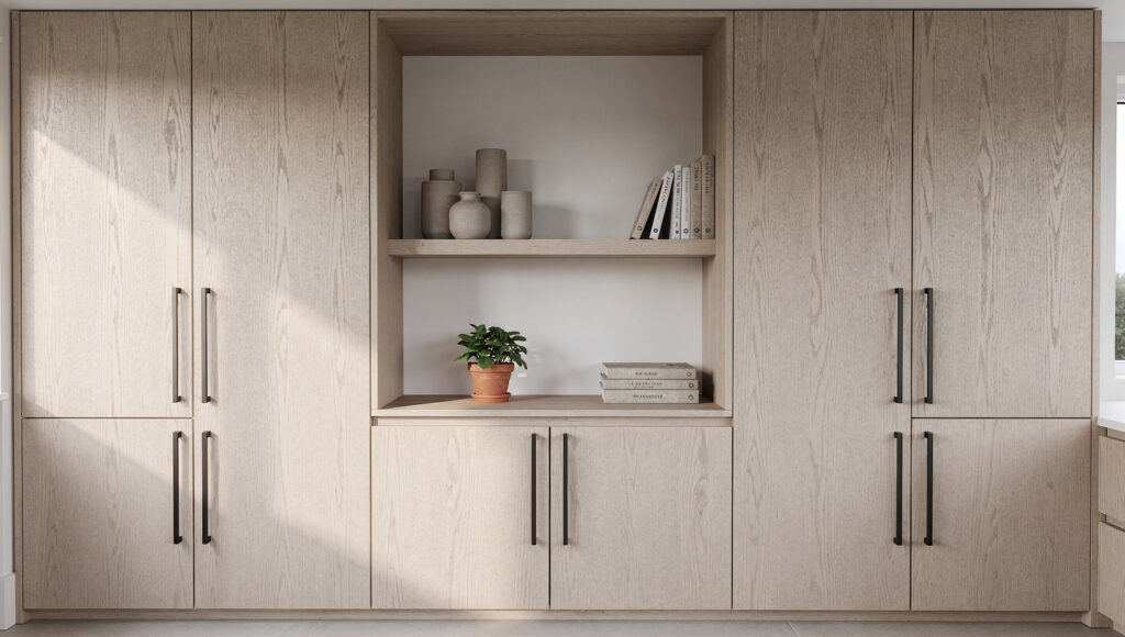 A biophilic kitchen showing a full run of rift-sawn white oak flat-panel cabinets with matte black bar pulls, interrupted by one open wood shelf section holding three matte ceramic vessels, a terracotta plant pot, and linen-covered cookbooks, breaking the closed cabinet plane with honest displayed objects